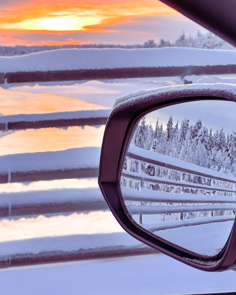 tramonto dallo specchietto dell'auto su un fiume della lapponia finlandese