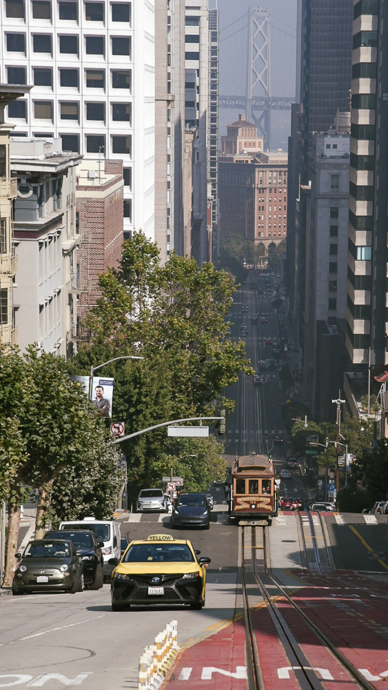 Discesa tipica di san Francisco con Taxi giallo e cable car in arrivo