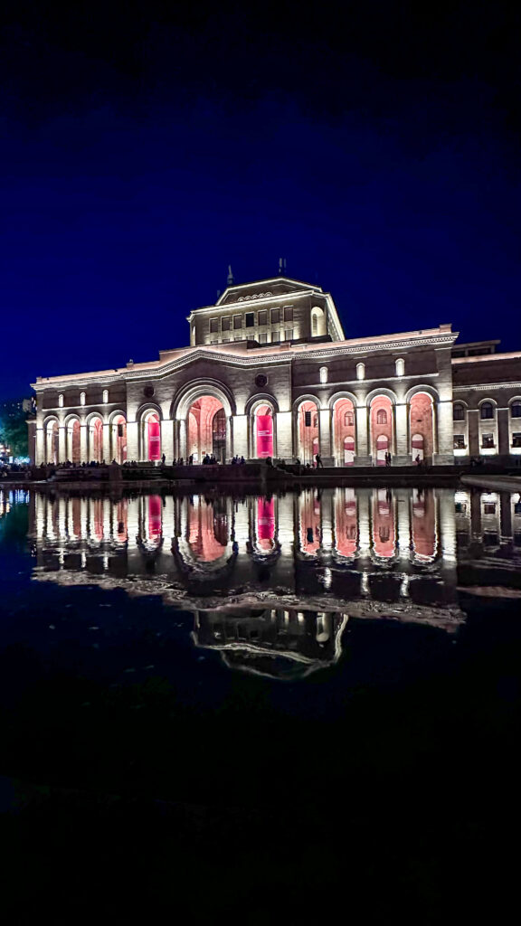 Museo di storia nazionale armena a Yerevan di notte illuminato che si specchia nella fontana antistante