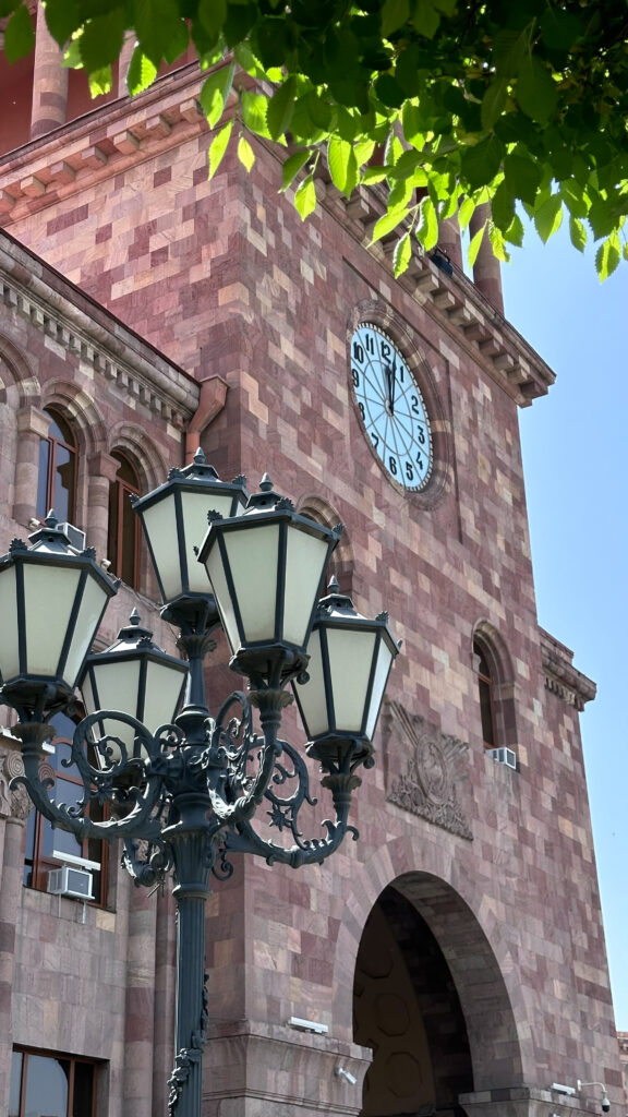 immagine laterale dell'orologio di un palazzo governativo con facciata in tufo armeno di colore rosa a piazza della Repubblica, a Yerevan