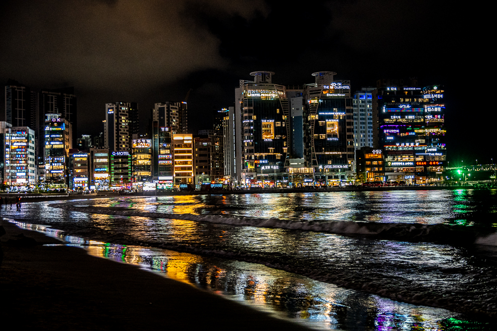 Busan, spiaggia di Gwangalli di notte, con insegne luminose che si riflettono nel mare