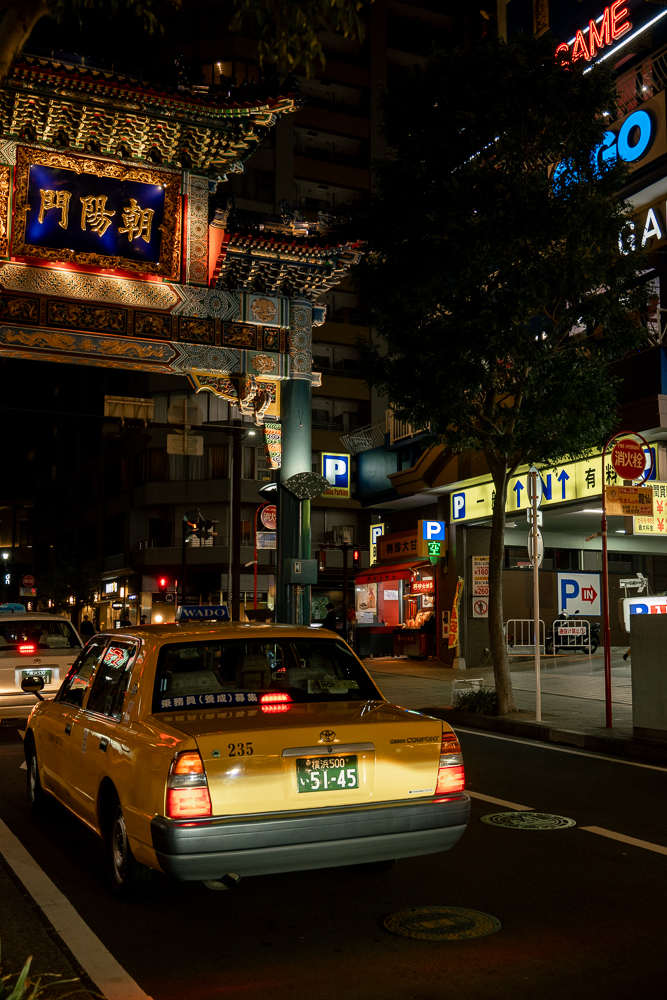 china town di yokohama di sera, con un taxi che passa sotto la porta di ingresso
